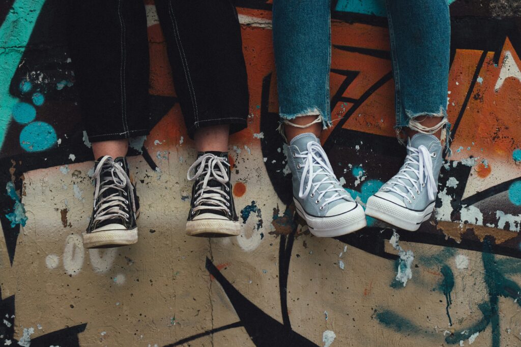 feet of youth sitting on a wall