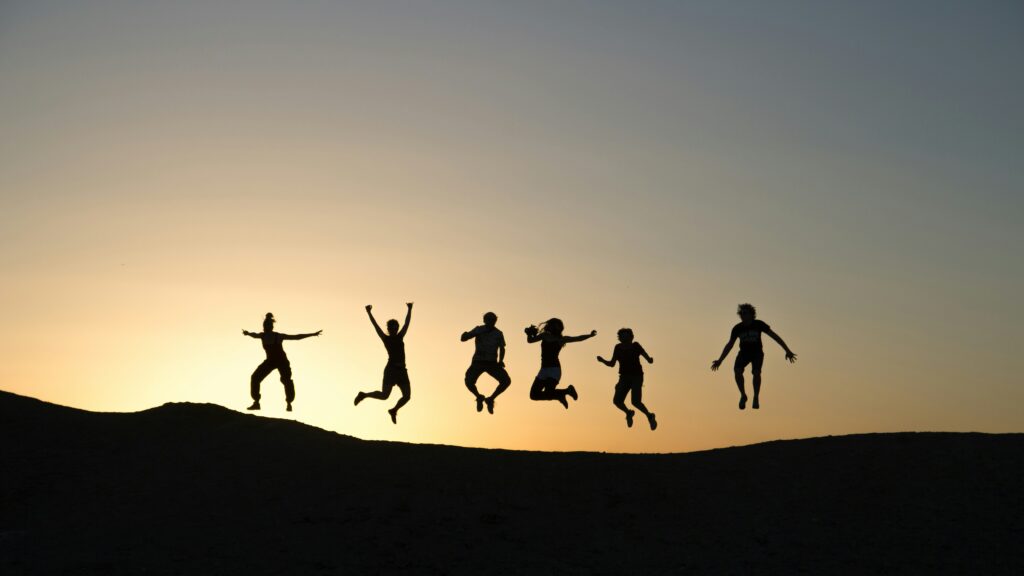 silhouettes of youth jumping at sunset